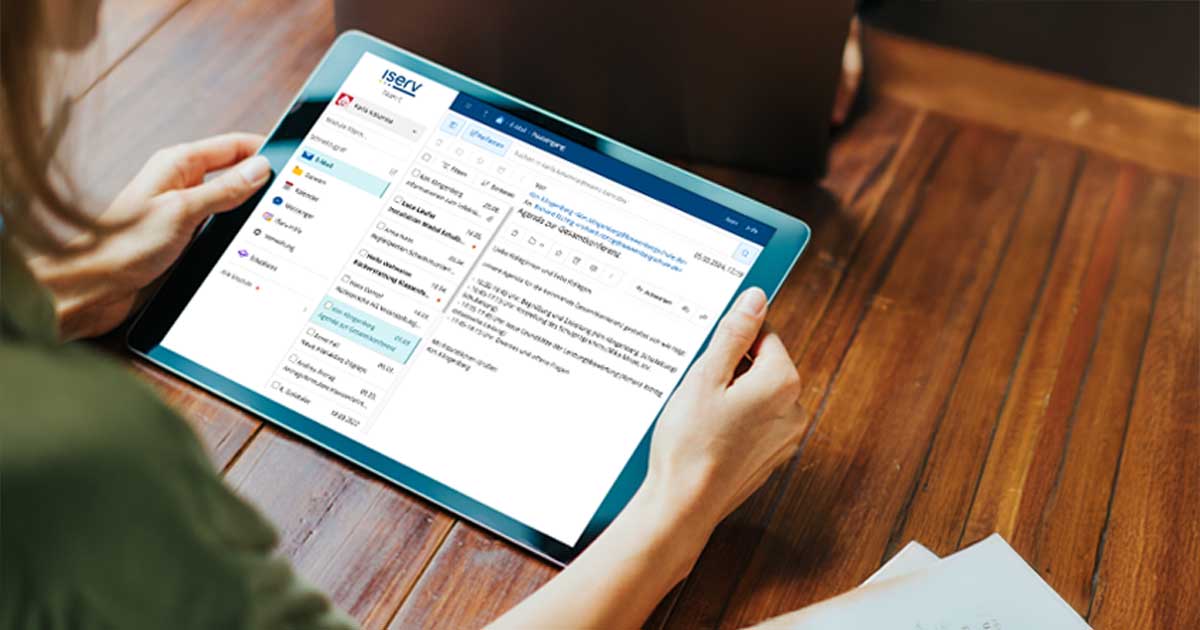 Eine Frau im Anschnitt hält ein Tablet in beiden Händen auf dem das E-Mail-Modul der IServ Schulplattform abgebildet ist.