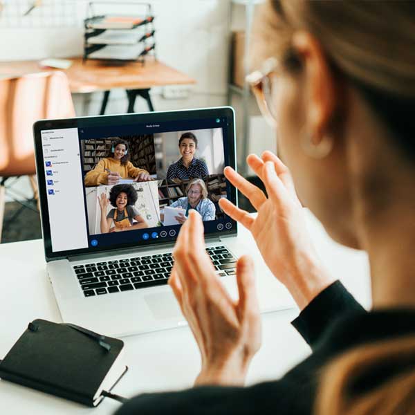 Eine Frau im rechten Bild-Anschnitt spricht mit vier verschiedenen Leuten über ihren Laptop in einer Videokonferenz.