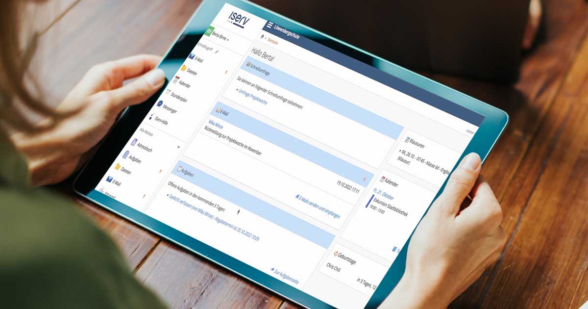 Eine Frau im Anschnitt des Bildes hält ein Tablet auf dem die Startseite der IServ Schulplattform zu sehen ist.
